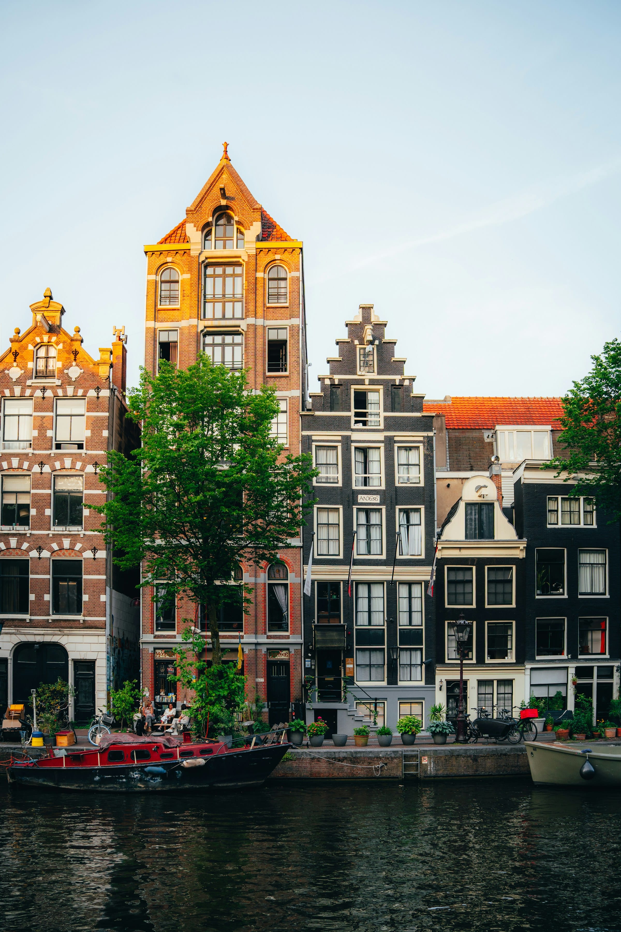 Amsterdam canal at dusk, lit gabled houses reflected in still water